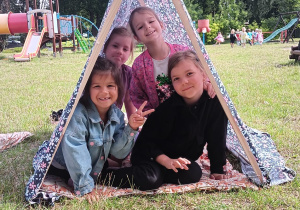 dziewczynki pod złożonym namiotem w ogrodzie przedszkolnym