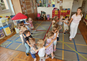 dzieci bawią się w pociąg, który prowadzi pani