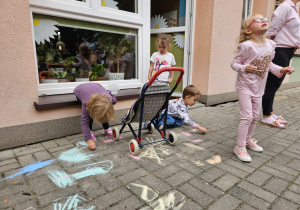 przedszkolaki rysują kredą na trasie przedszkolnym