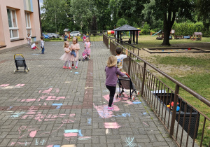 przedszkolaki rysują kredą na trasie przedszkolnym