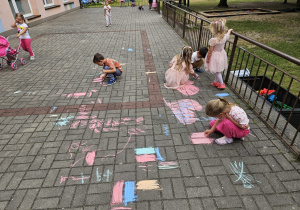 przedszkolaki rysują kredą na trasie przedszkolnym