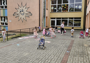dzieci bawią się na tarasie przedszkolnym wózkami i lalkami