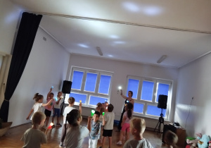 dzieci bawią się światłem - świecą latarkami na sufit sali