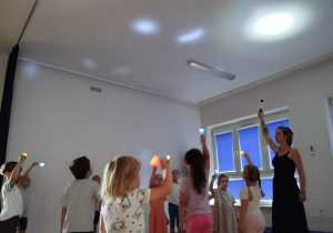 dzieci bawią się światłem - świecą latarkami na sufit sali