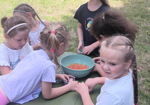 dziewczynki bawią się koralikami na stoliku ogrodowym