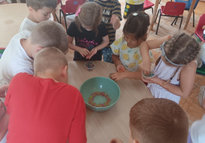 dzieci bawią się koralikami w sali przedszkolnej