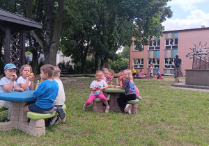 przedszkolaki piknikują na stołach ogrodowych
