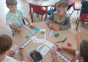 dzieci mocują kliszę w aparacie i rysują na klatkach kliszy obrazki