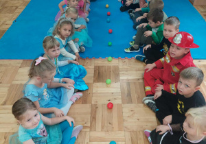 dzieci bawią się piłeczkami siedzą w dwóch rzędach