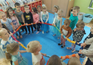 przedszkolaki w sali w czasie zabaw z kolorową liną krążą w kole