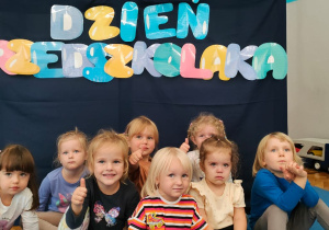 zdjęcie dzieci przed zasłoną z napisem dzień przedszkolaka