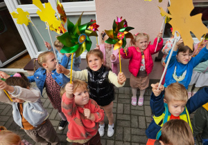 dzieci na tarasie pokazują swoje wiatraczki i liście