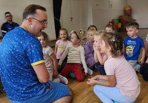 dzieci siedzą na piłkach i rozmawiają z trenerem