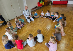 dzieci siedzą w kole z trenerem