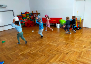 przedszkolaki biegną z piłkami uniesionymi nad głową