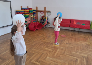 dziewczynki stoją w kókach i trzymają piłkę na głowie