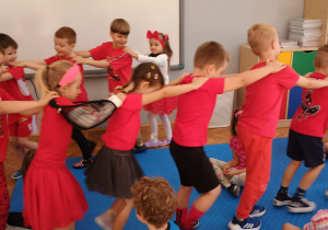 dzieci tańczą w czerwonym wężu trzymając się za ramiona
