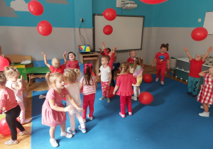 dzieci podrzucają i chwytają czerwone balony