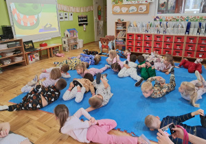 dzieci wykonują ćwiczenia na macie - próbują wykonać tzw. foczkę