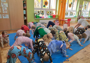 pani psycholog z dziećmi wykonuje ćwiczenie z jogi - pies