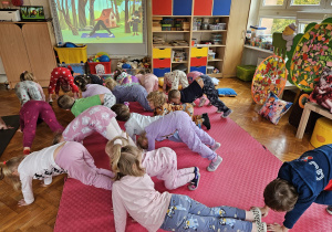 pani psycholog z dziećmi wykonuje ćwiczenie z jogi - pies