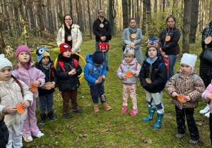 przedszkolaki stoją w lesie w kole wraz zrodzicami i nasłuchują odgłosów lasu