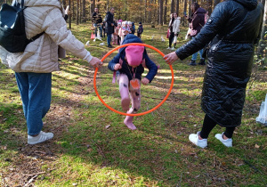 dzieci zdobywają sprawność ruchową - dziewczynki - wiewiórki biegną i wskakują do dziupli wchodząc do koła trzymanego przez mamy