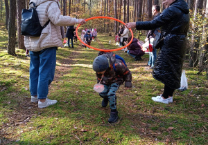 dzieci zdobywają sprawność ruchową - chłopcy -liski biegną i wchodzą do norki przechodząc pod kołem trzymanym przez mamy