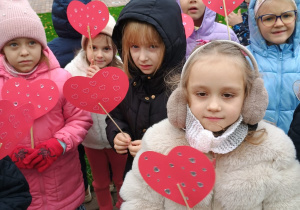 dziewczynki stoją z ozdobionymi czerwonymi serduszkami