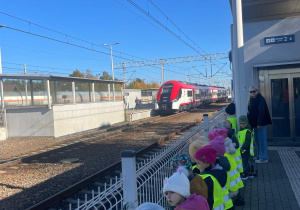 przedszkolaki na dworcu kolejowym w Zduńskiej Woli obserwują nadjeżdżający pociąg osobowy