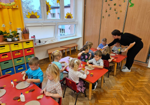 mama pomaga dzieciom podczas przyklejania liści