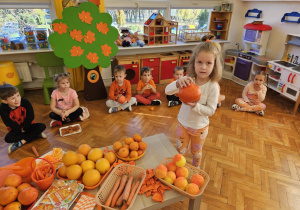 dziewczynka trzyma w rękach pomarańczową dynię