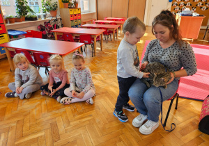 kot siedzi na kolanach mamy a chłopiec go głaszcze
