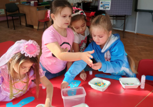 dziewczynki wykonują pracę plastyczną przy stoliku