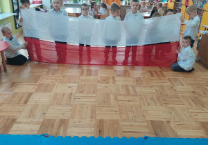 chłopcy trzymają długą flagę polską
