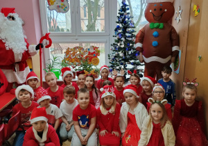 zdjęcie grupowe przedszkolaków z grupy VII z Mikołajem i Piernikowym Ludzikiem przy choince