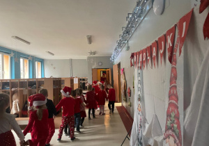 przedszkolaki idą w korowodzie prowadzonym przez Mikołaja od sali do sali i zbierają dzieci