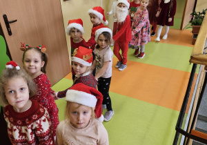 przedszkolaki idą w korowodzie prowadzonym przez Mikołaja od sali do sali i zbierają dzieci
