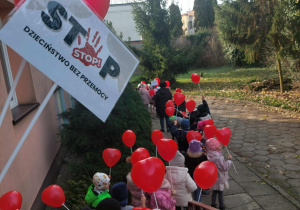 przedszkolaki wychodzą z budynku przedszkola z balonami