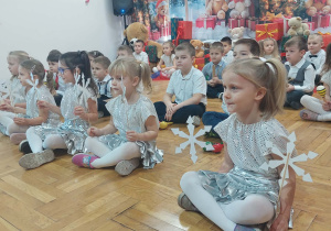 dzieci siedzą w rzędach ze śnieżynkami i instrumentami