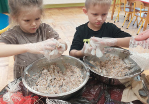 przedszkolaki w rękawiczkach jednorazowych formują kule tłuszczowe z ziarnami