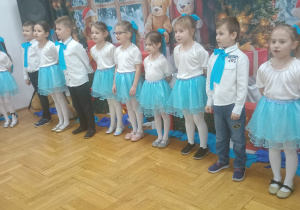 dzieci śpiewają piosenkę stojąc w półkolu