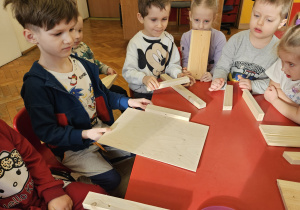 dzieci oglądają drewniane elementy na karmnik