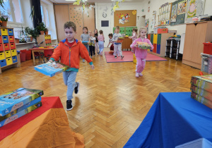 dzieci budują wieżę z książek przenosząc je jak najszybciej na stolik