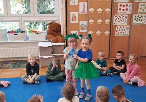 dziewczynki w strojach zielonym i niebieskim trzymają niebieską kropelkę