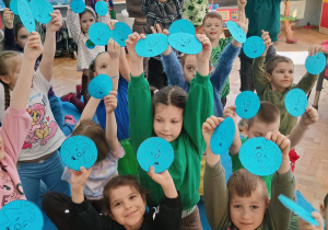 przedszkolaki pokazują emblematy wesołej i smutnej Ziemi