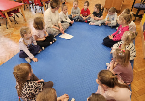 pani Kasia siedzi z dziećmi w kole i rozmawia z nimi