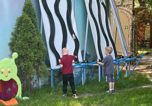 chłopcy bawią się samochodami zawieszonymi na sznurkach