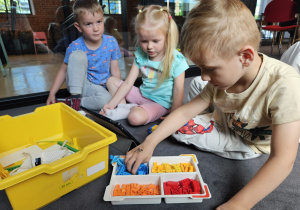 dzieci składają zabawkę z klocków lego wg instrukcji