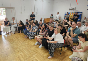 zgromadzeni rodzice oglądają popisy dzieci na scenie